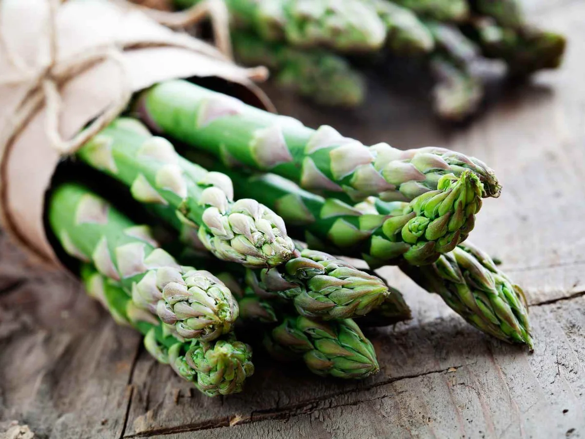 A hand holding a bunch of fresh asparagus spears