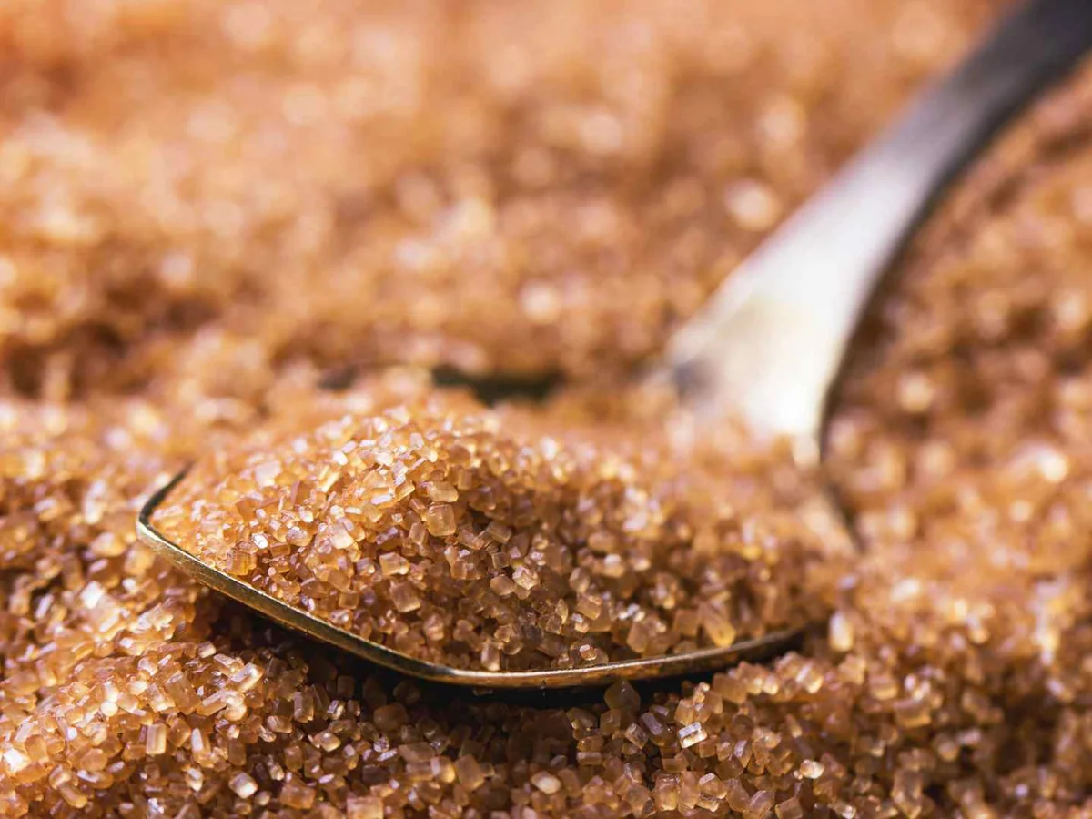 Coarse brown sugar crystals with a metal spoon