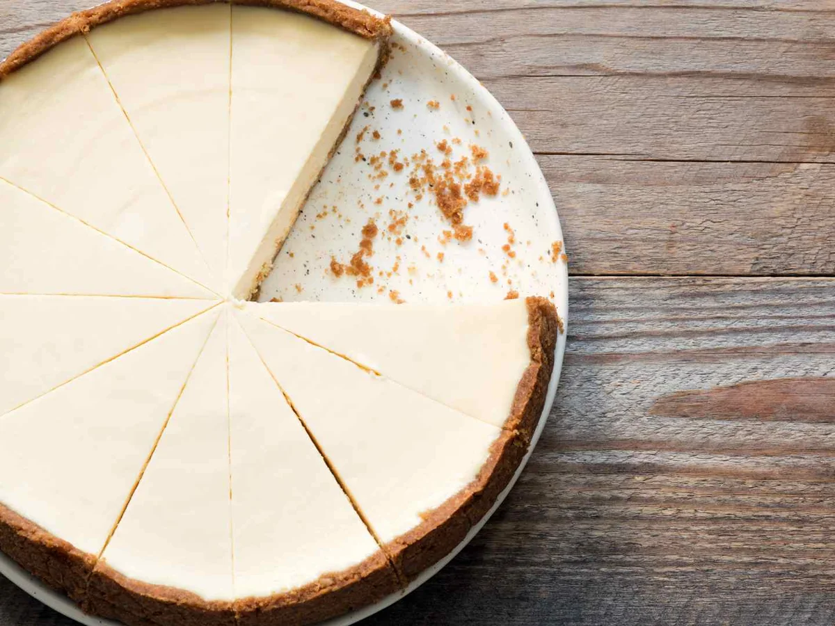 A plain round cheesecake with one slice removed