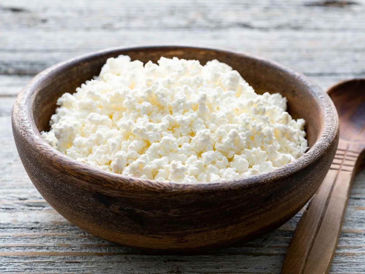 Cottage cheese in a wooden bowl beside a spoon