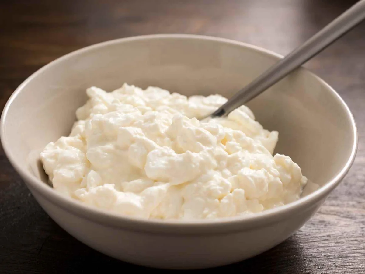 Cottage cheese in a white bowl with a metal spoon