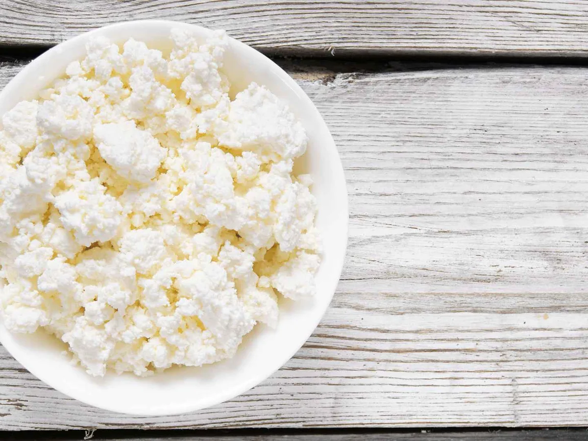 An overhead bowl of cottage cheese on a gray wooden table