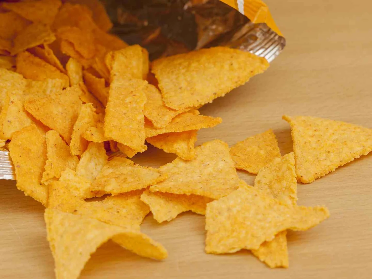 Orange triangular tortilla chips on a wooden surface