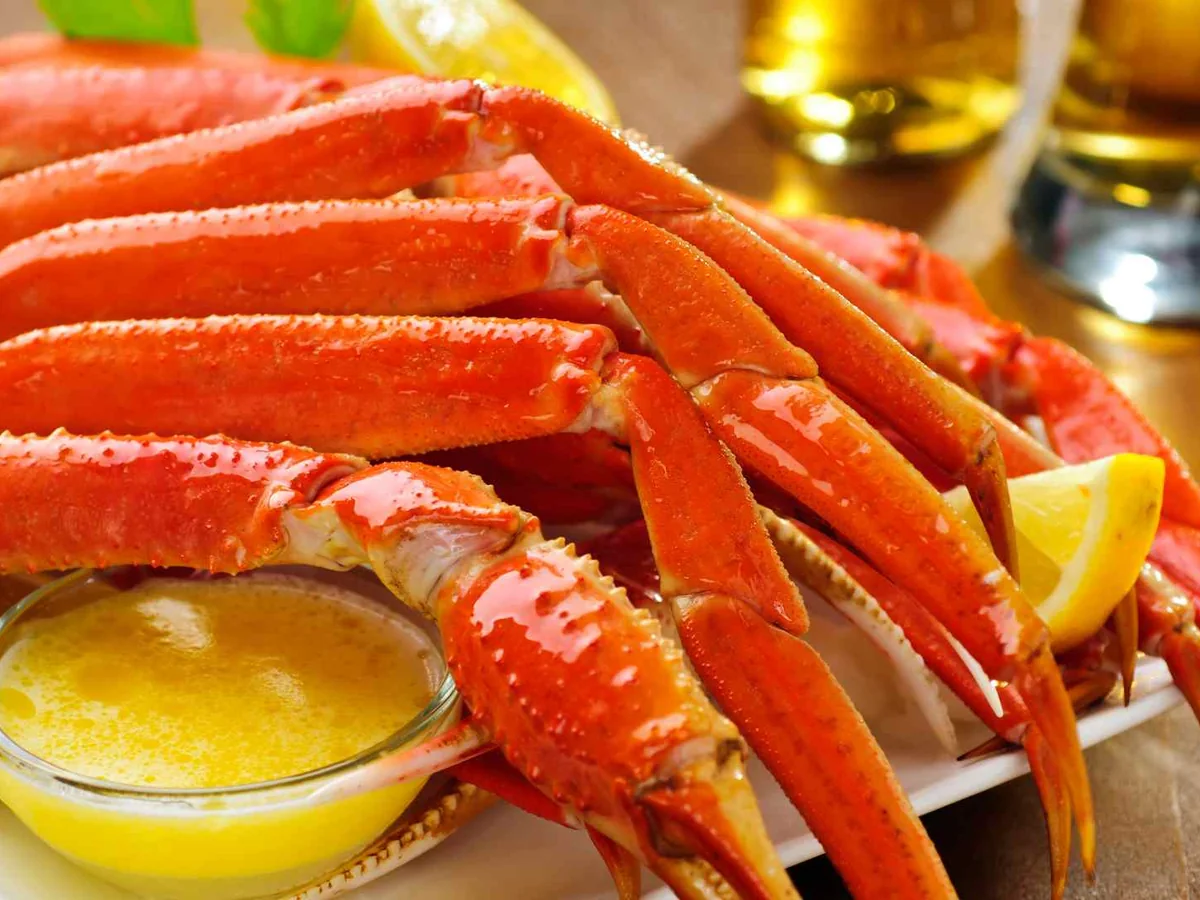 Cooked red crab legs beside melted butter and lemon