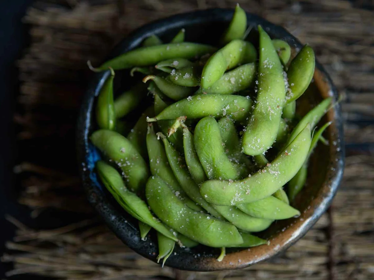 Salted edamame pods in a dark bowl