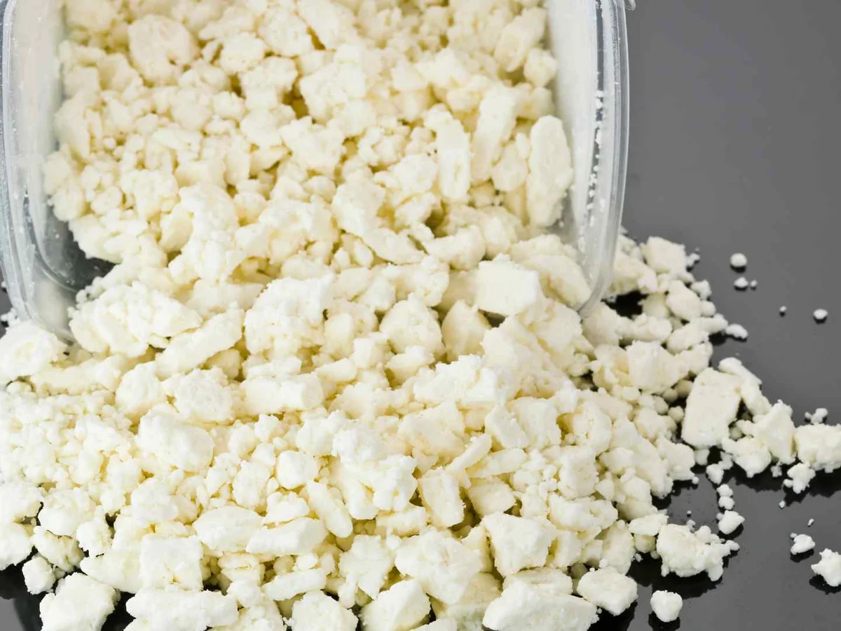 Crumbled feta cheese spilling from a clear container