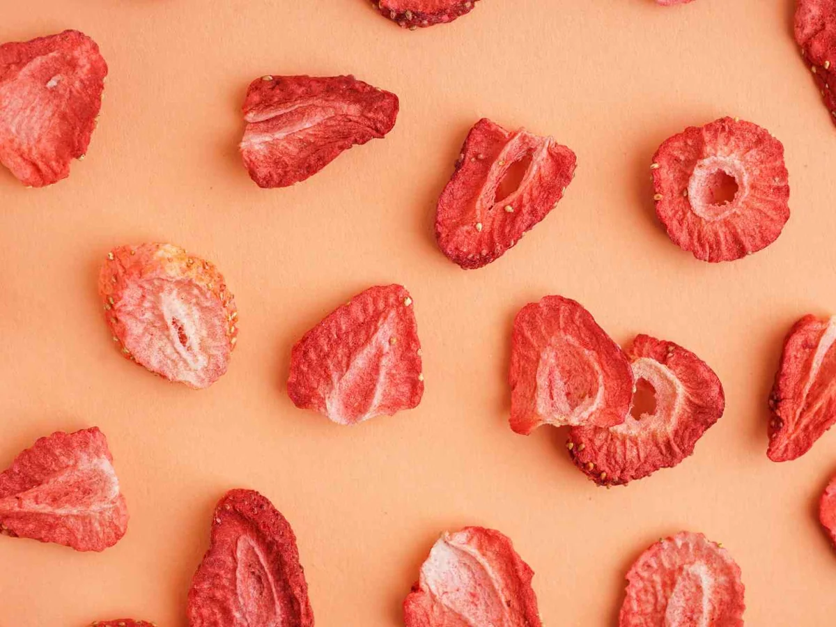 Freeze-dried strawberry pieces scattered on a pink surface