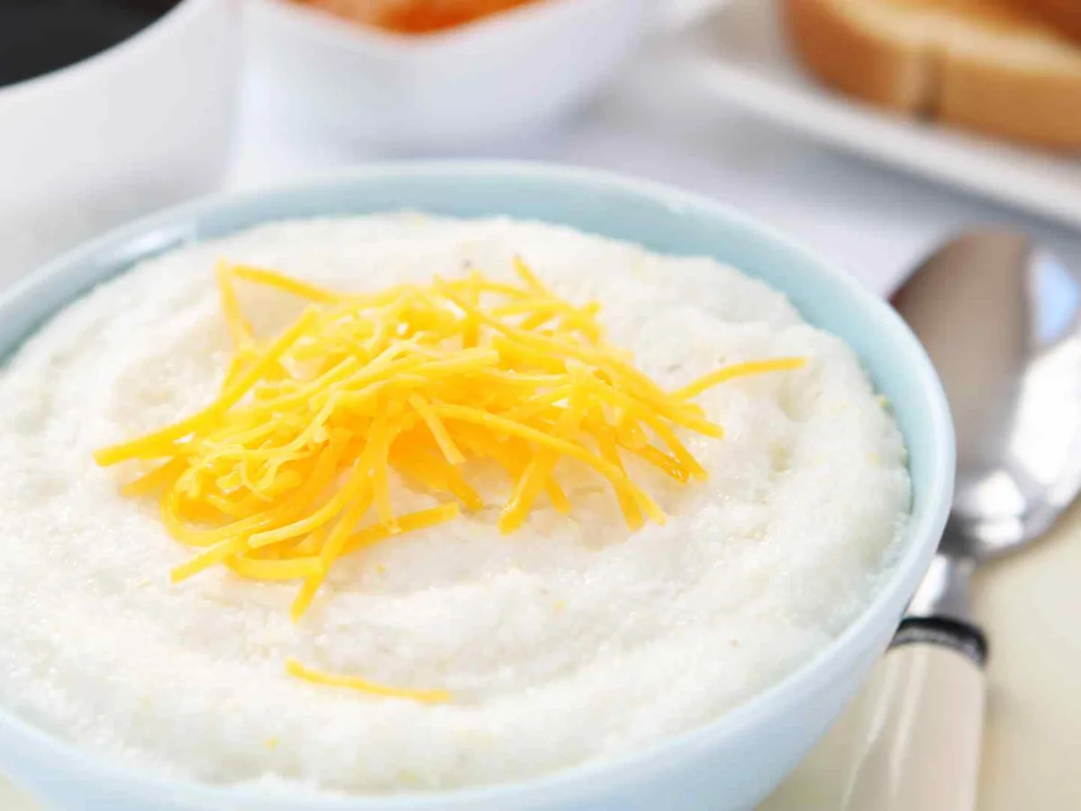 A close-up bowl of grits topped with shredded cheese