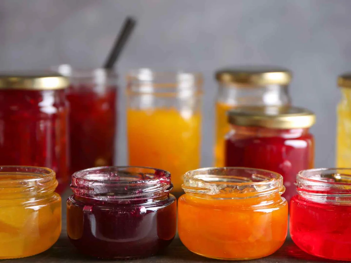 Assorted red, orange, and yellow jellies in glass jars