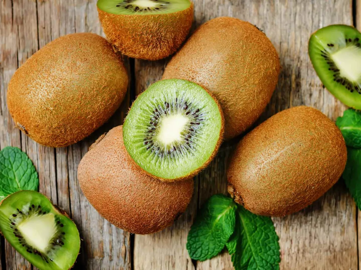 Whole and halved kiwi fruit on a wooden table