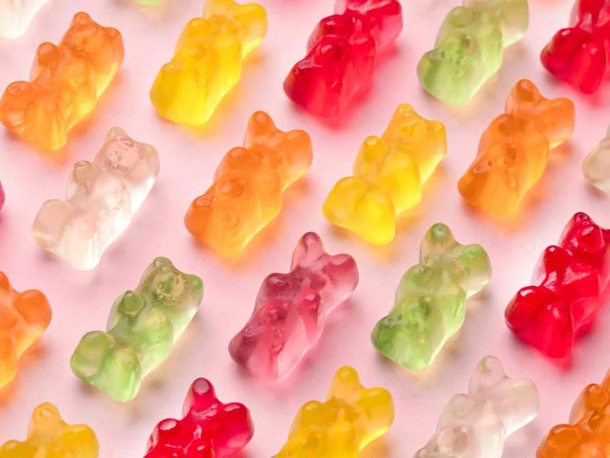 Multicolored gummy bears arranged on a pale pink surface