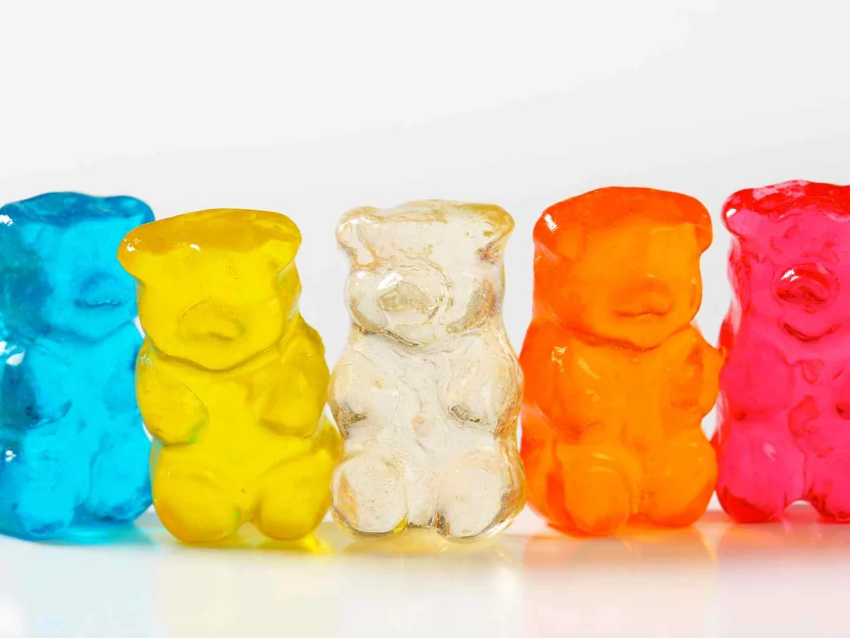 Five large gummy bears in different colors on white