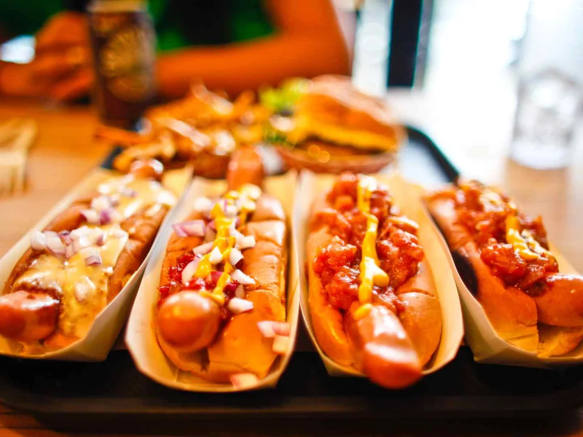 Several dressed hot dogs arranged on a wooden table