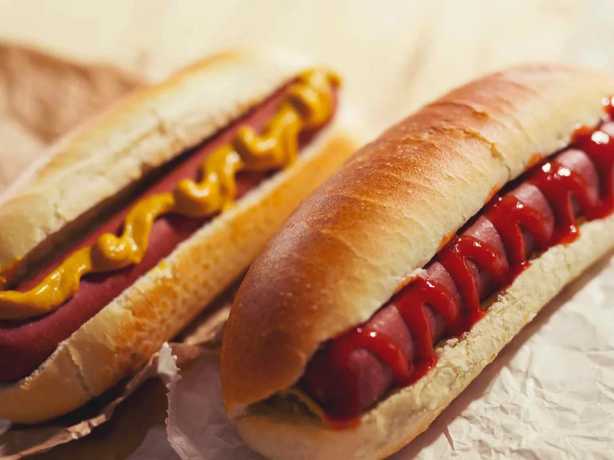Two hot dogs in buns with ketchup and mustard