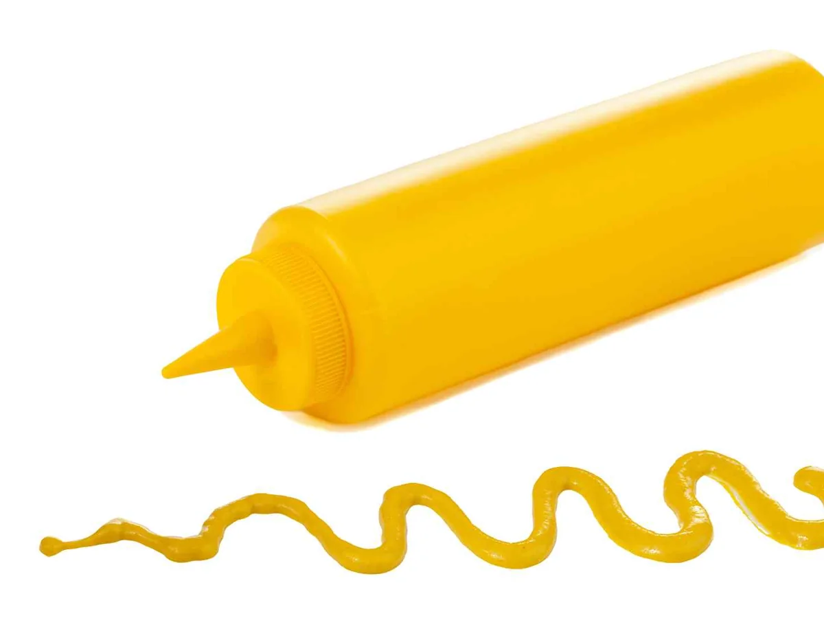 A plain yellow squeeze bottle dispensing mustard
