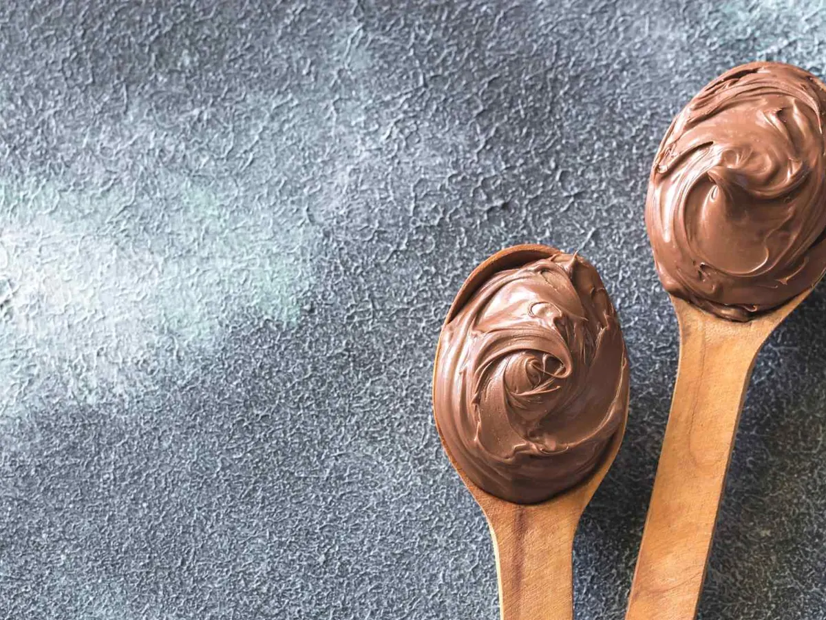 Two wooden spoons coated with chocolate spread