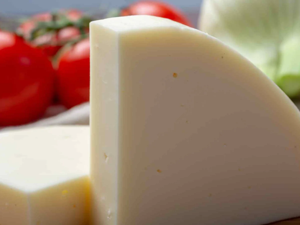 A pale wedge of provolone cheese beside tomatoes