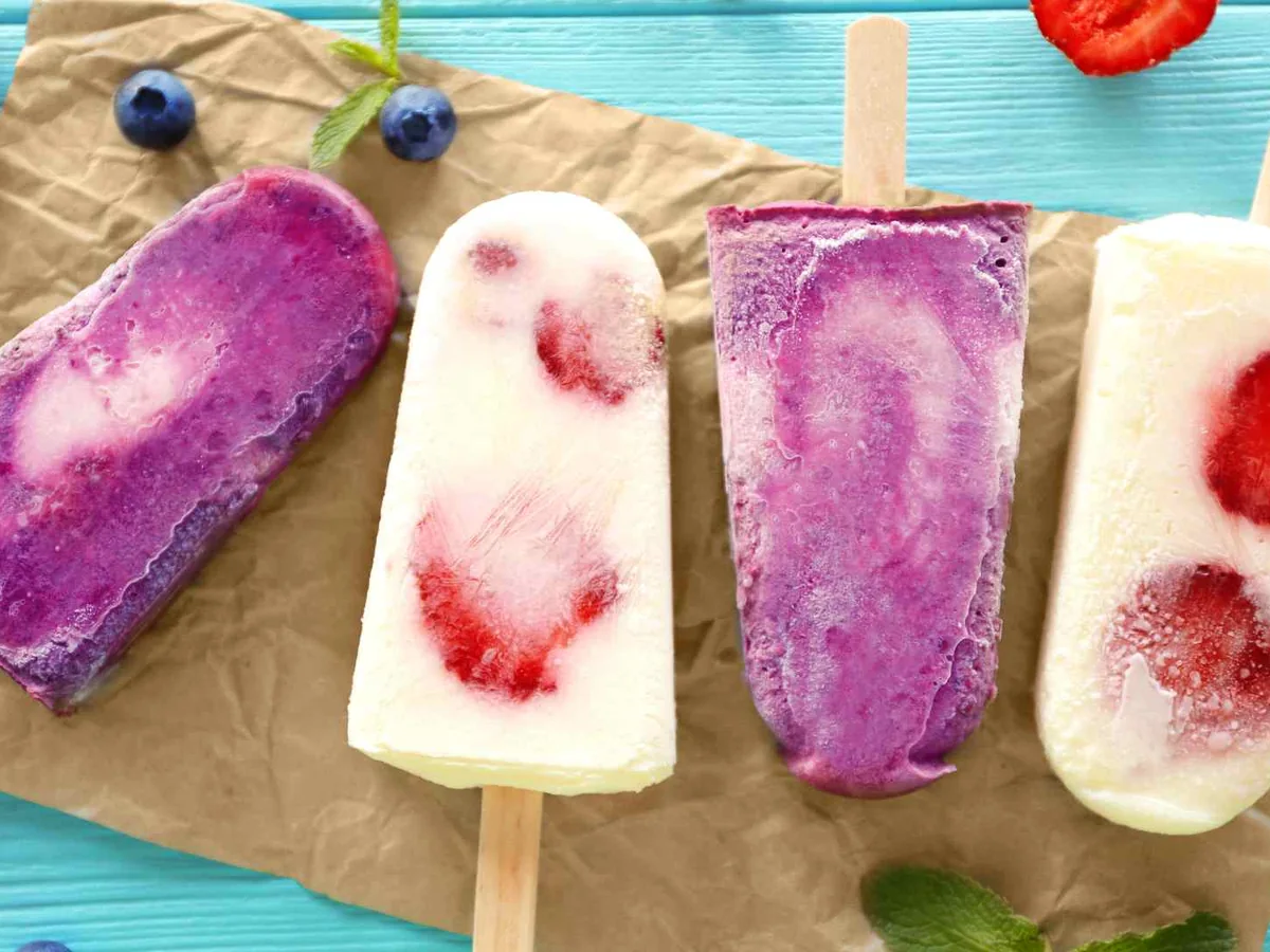 Fruit popsicles on parchment with berries