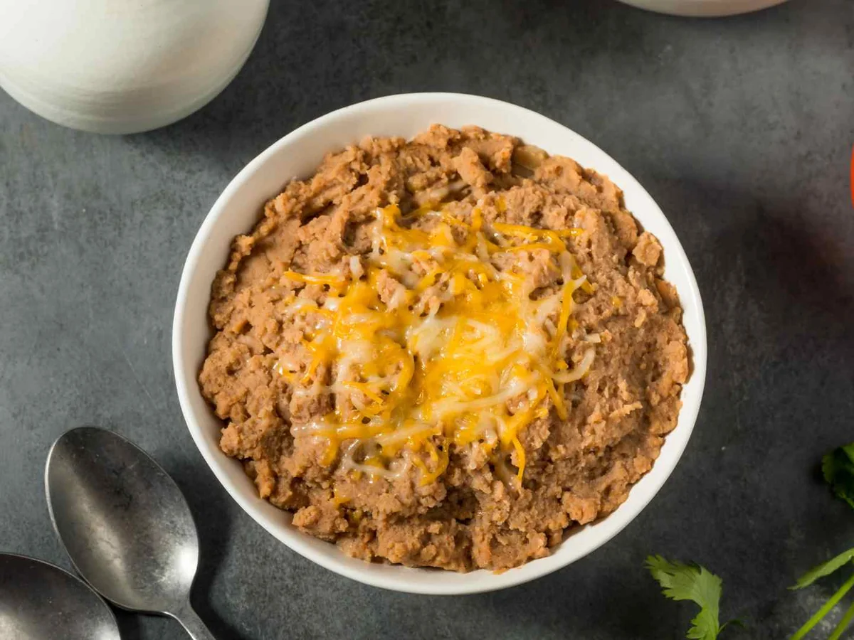 A baked bowl of refried beans topped with melted cheese