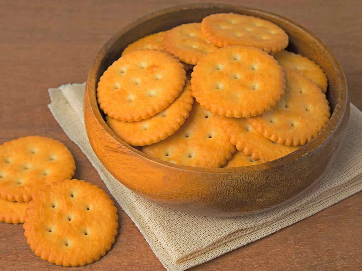 Round buttery crackers arranged in and around a bowl