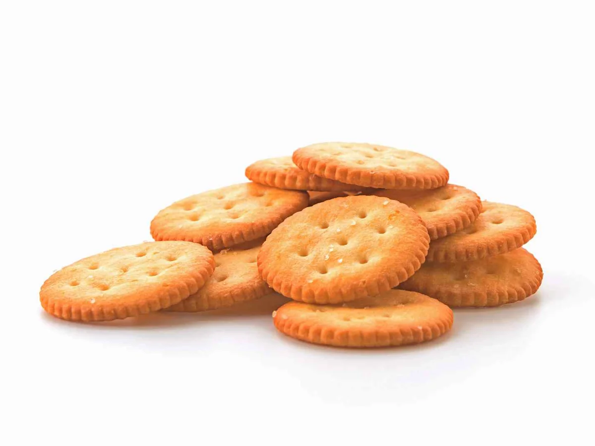A scattered pile of round buttery crackers on white