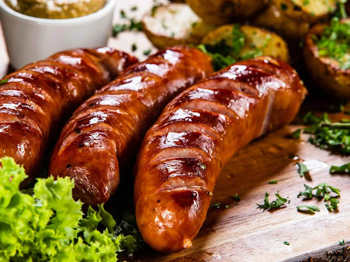 Three browned sausages on a plate with vegetables