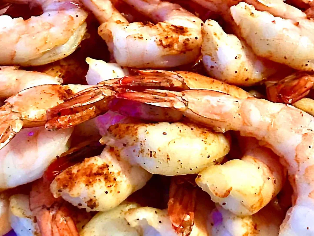 Cooked shrimp with tails spread across a grill