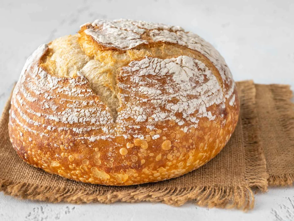 A round scored sourdough loaf on burlap