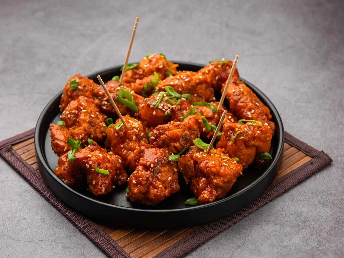 A dark bowl of spicy red-sauced chicken