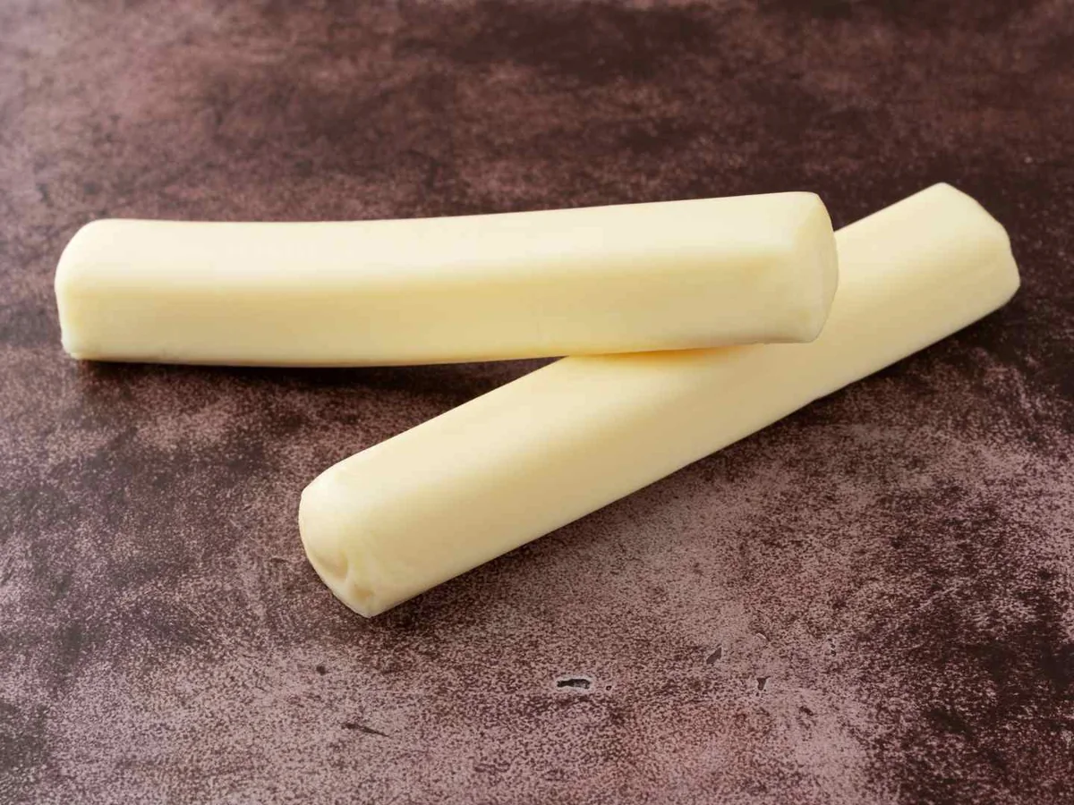 Three pale string cheese sticks on a dark surface