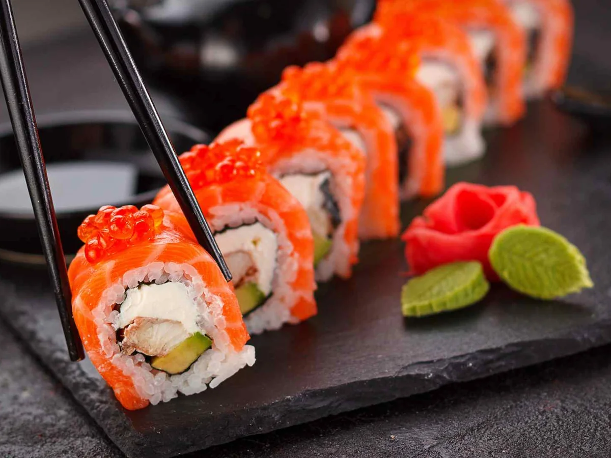 A row of bright orange-topped sushi rolls