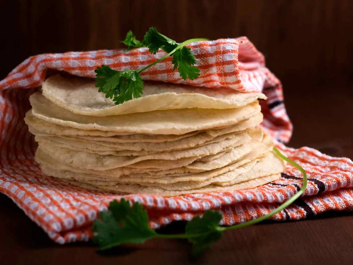 A stack of tortillas wrapped in a red checked cloth