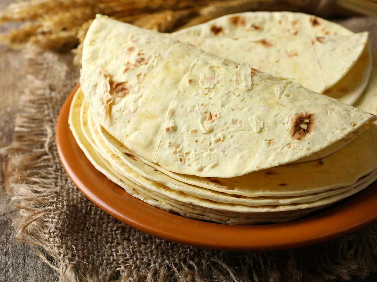 A stack of flour tortillas on a brown plate