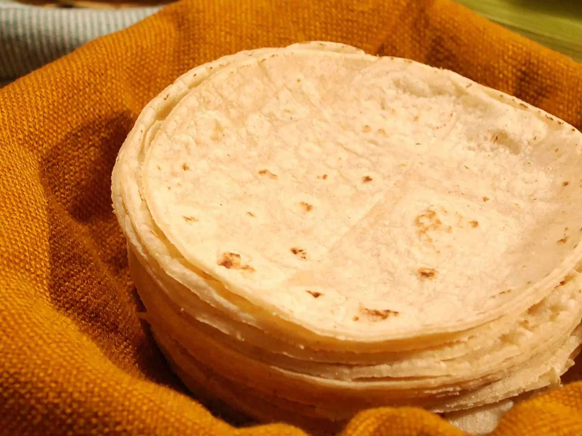 A tall stack of tortillas on orange fabric
