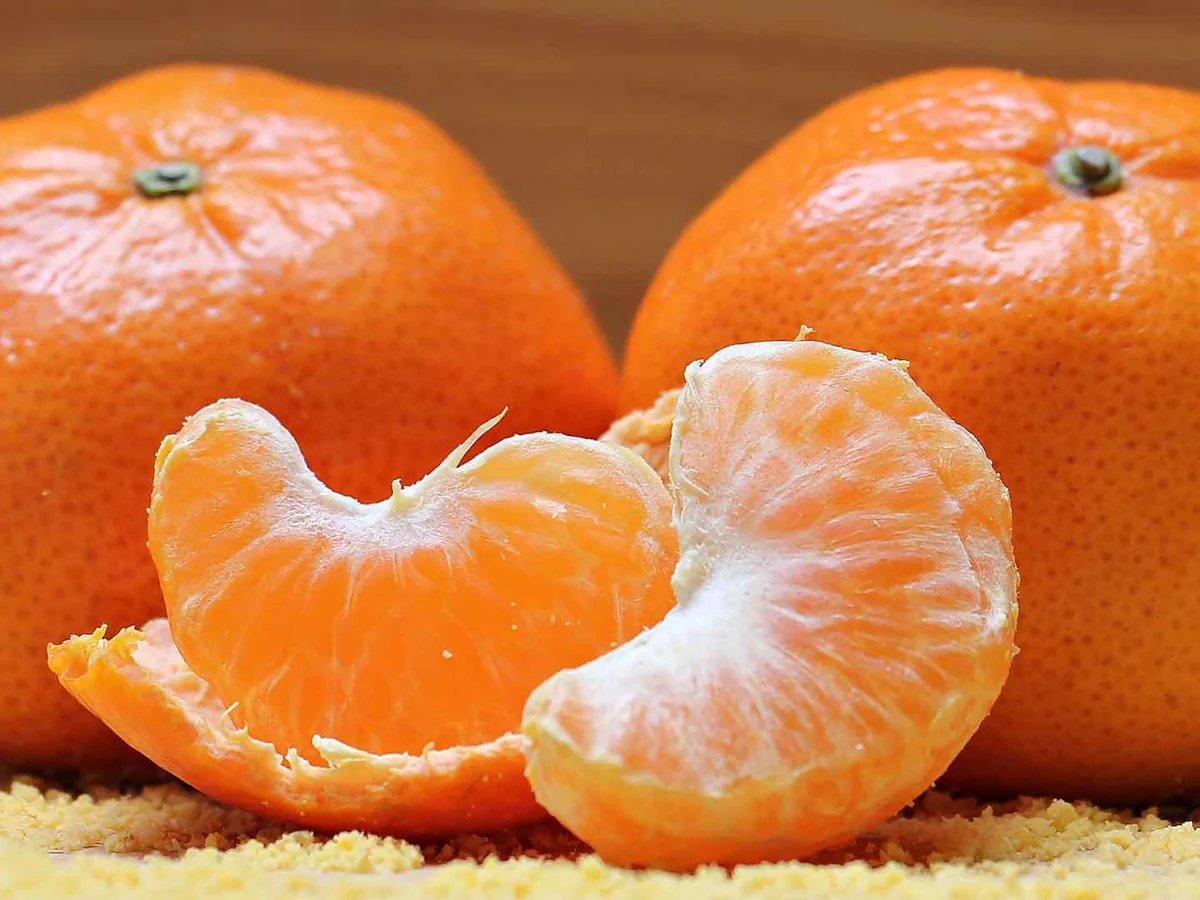 Whole and peeled tangerines against an orange background