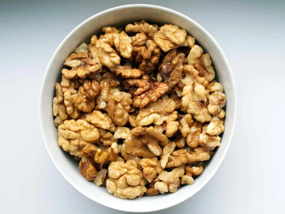 Walnut pieces in a white bowl viewed from above