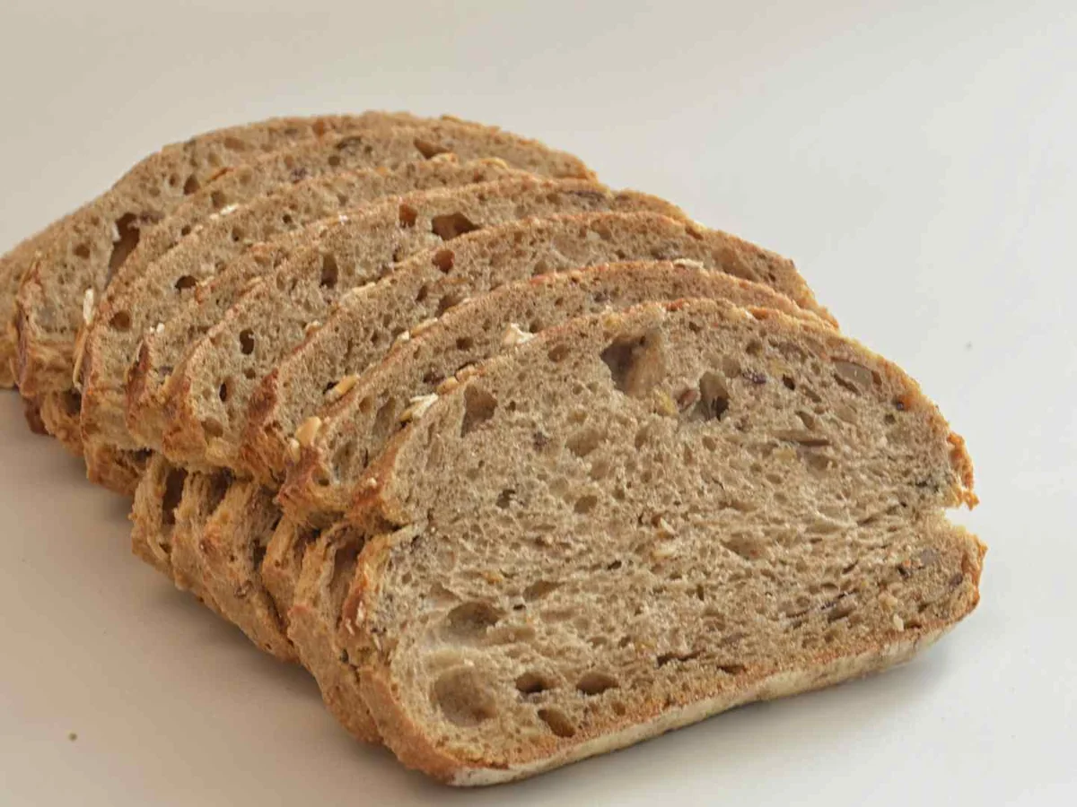 Several slices of brown wheat bread on a pale surface