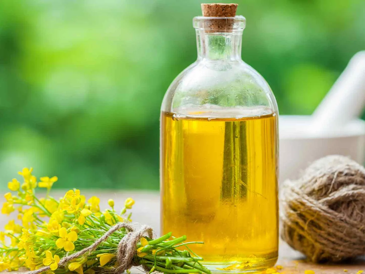 Cooking oil in a corked bottle beside yellow flowers