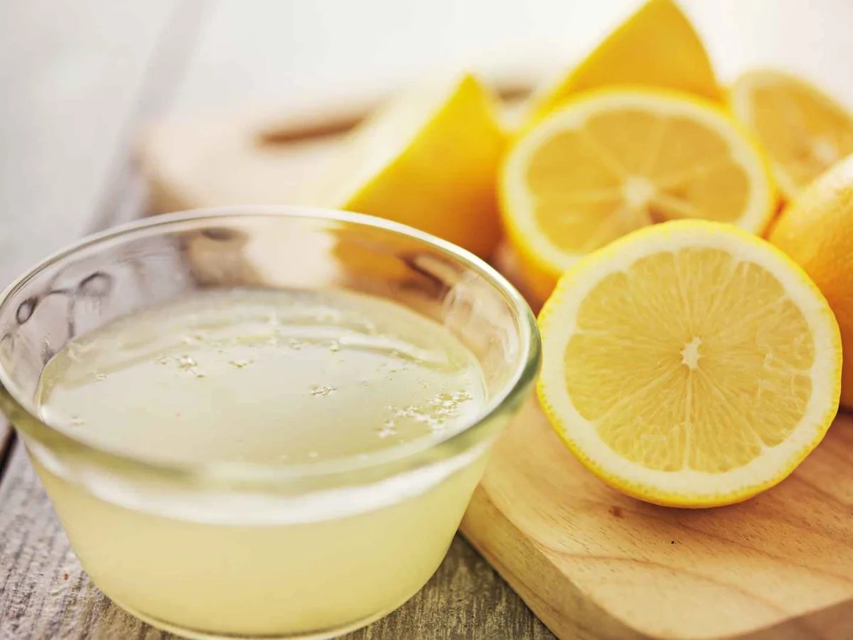 A small bowl of lemon juice beside halved lemons