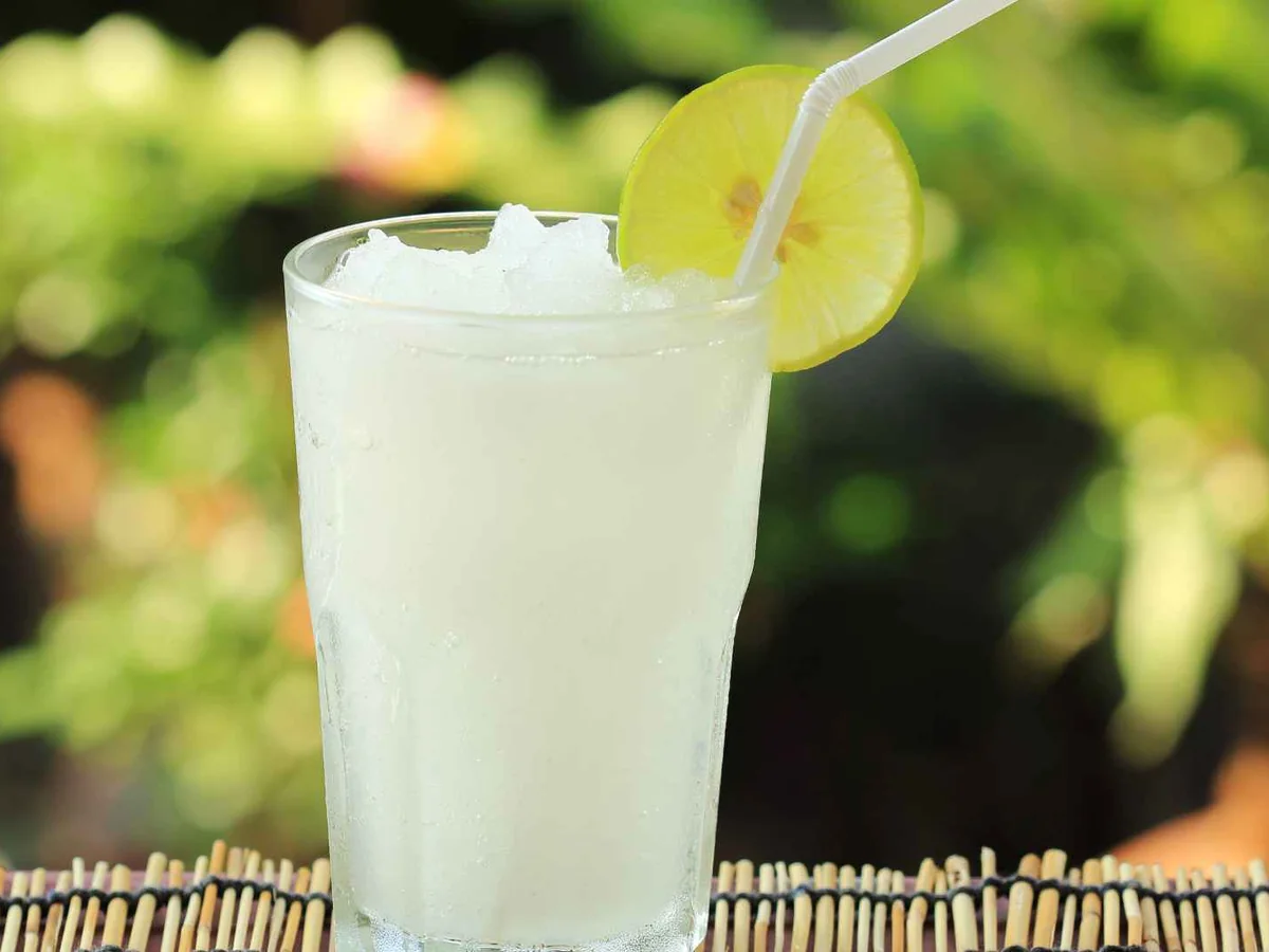 A pale lemon drink with a straw and lime slice